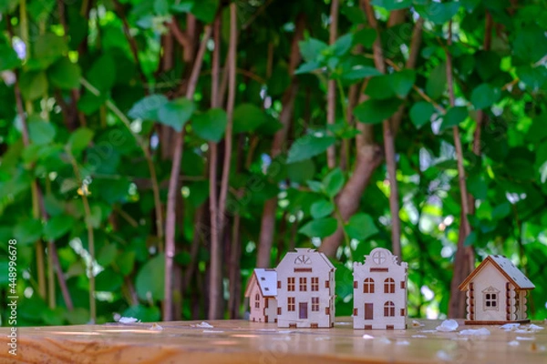 Fototapeta small houses on a wooden table with a background of greenery