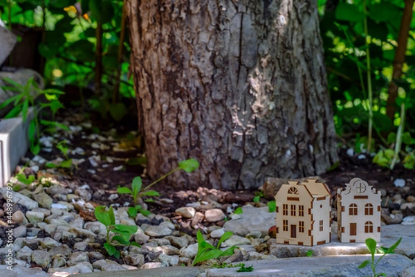 Fototapeta toy houses on a stone slab against the background of a tree trunk