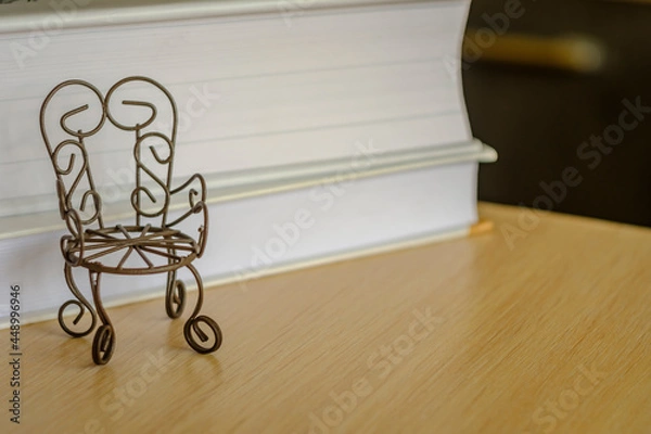 Fototapeta toy iron chair on a wooden table, with a background of books