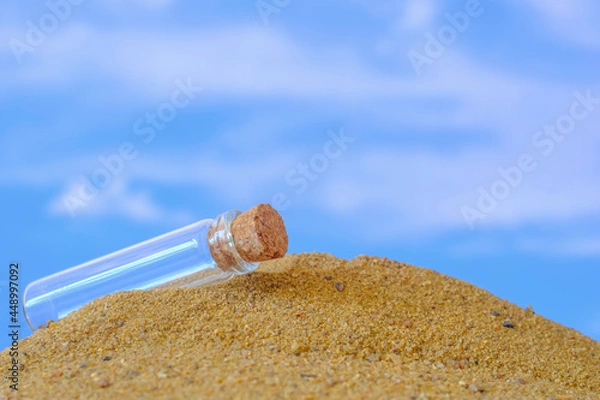 Fototapeta small glass jar with a cork lying on the sand