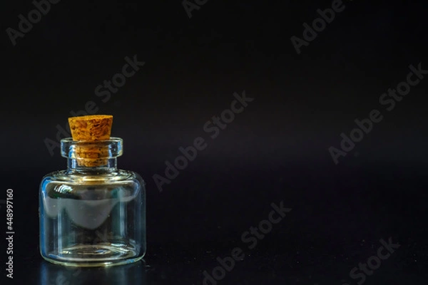 Fototapeta small glass jar with a cork on a black background