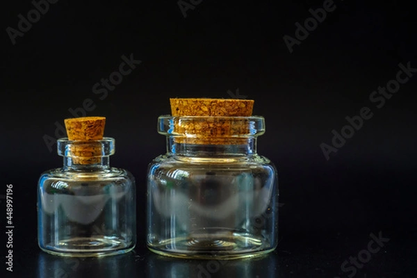 Fototapeta small glass jars with a cork on a black background