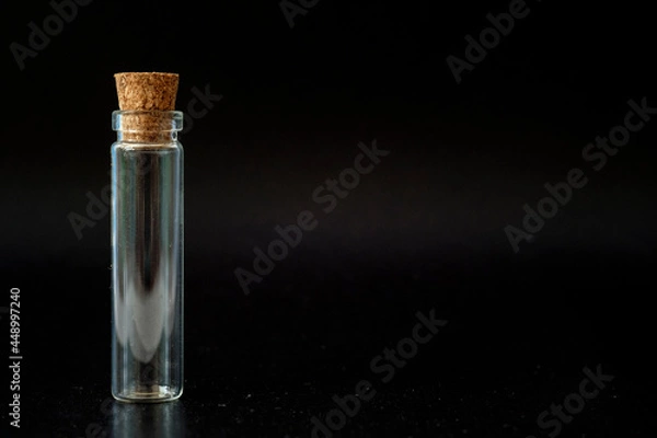 Fototapeta small glass jar with a cork on a black background