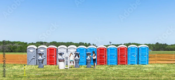 Fototapeta Row of colorful mobility lavatory and washbasin, hygiene facility for people at outdoor event. Public temporary restroom at a park, attendees using amenity during festival, convenience and sanitation
