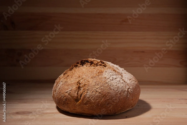 Obraz Handmade fresh wheat bread on wooden background in the contrast light. horizontal frame side view with space area for text or design