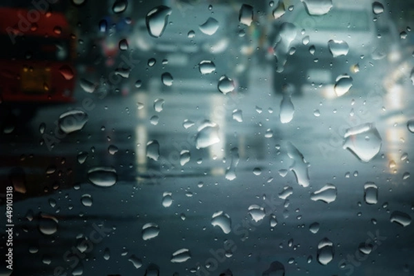 Fototapeta Blurry cars run through wet road in city during hard rain fall at night,view through the window.Selective focus and very shallow depth of field composition.