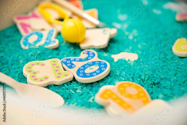 Obraz Kid learning numbers through game. Sensory activity with colored rice and wooden numbers. Educations at home, pre-school education, Montessori methodology