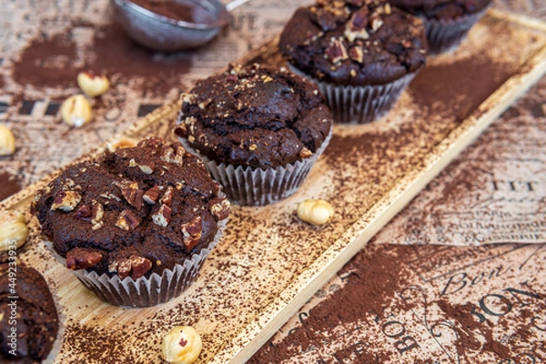 Obraz Healthy gluten free chocolate muffins with pecan nuts on a wooden serving board. Homemade, freshly baked delicious cupcakes with a crispy top and cocoa powder. Nutrition concept, selective focus 