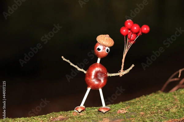 Fototapeta Funny crafted chestnut male with red balloons in front of black background standing on a mossy branch