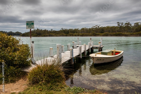 Fototapeta a small boat and wharf in a body of water