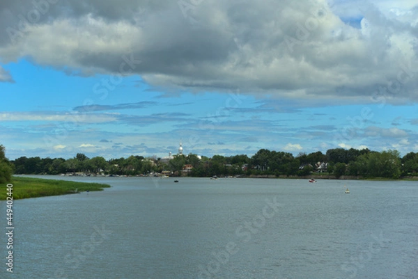 Fototapeta Islands of Boucherville national park in Lawrence (Laurent) River, Montreal, QC on a cloudy summer day. The trees and grass on the river banks. The marina od Boucherville at the background.