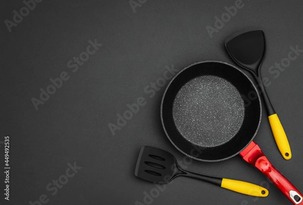 Obraz Frying pan with spades on black background. Top view. Space for text.