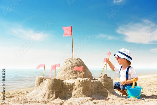 Obraz Kid play on the seashore on a hot sunny day. Little girl on the beach building a sand castle on summer vacation.