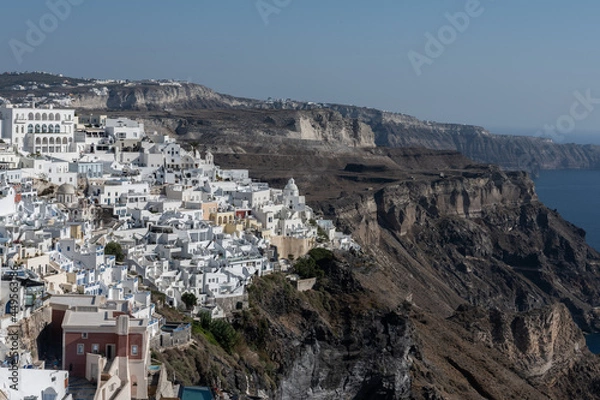 Fototapeta White top of buildings in Santorini, Greece with blue sky in a sunny warm day in July 2021.