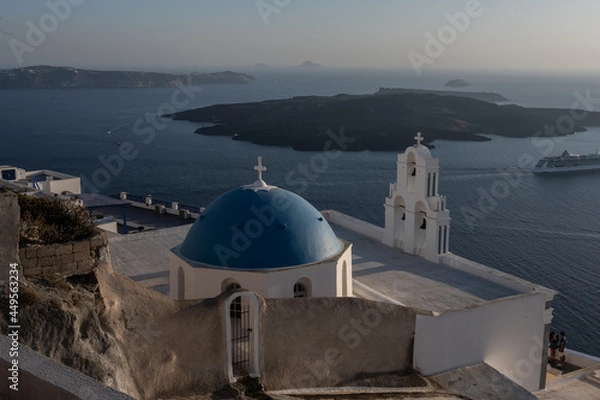 Fototapeta White top of buildings in Santorini, Greece with blue sky in a sunny warm day in July 2021.