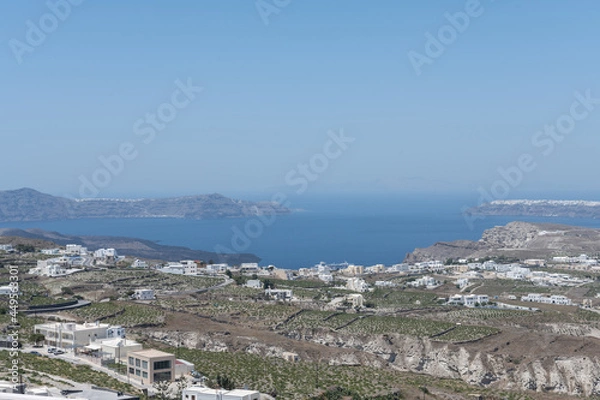 Fototapeta White top of buildings in Santorini, Greece with blue sky in a sunny warm day in July 2021.