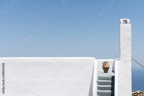 Fototapeta White stairs with a jar  of a buildings in Pyrgos Santorini, Greece with blue sky in a sunny warm day in July 2021.