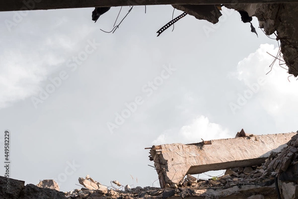 Fototapeta The ruins of the remains of a building with a concrete beam against the gray sky. Background.