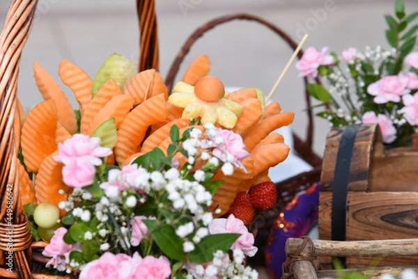 Fototapeta closeup of an edible fruit arrangement setup in a basket with flowers