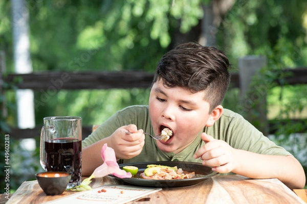 Obraz Niño latinoamericano, mexicano, sinaloense comiendo mariscos tostada de camaron acompañado con agua fresca