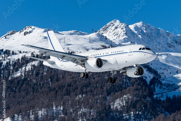 Fototapeta luxurious business jet landing with snow covered mountains in the background