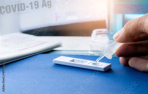 Obraz Hand holding sample tube and drops in the test device of covid 19 antigen self-test. Antigen test kit for detection of coronavirus infection. Rapid antigen test. Coronavirus diagnosis. Medical device.