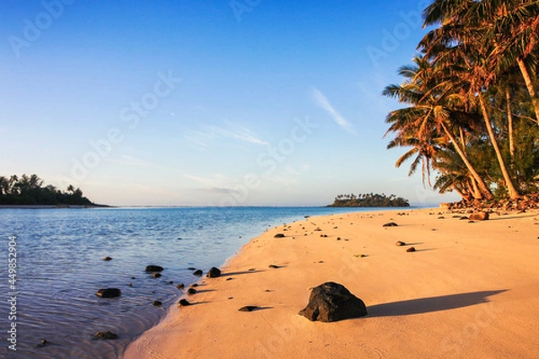 Fototapeta a sandy beach next to a body of water in cook islands