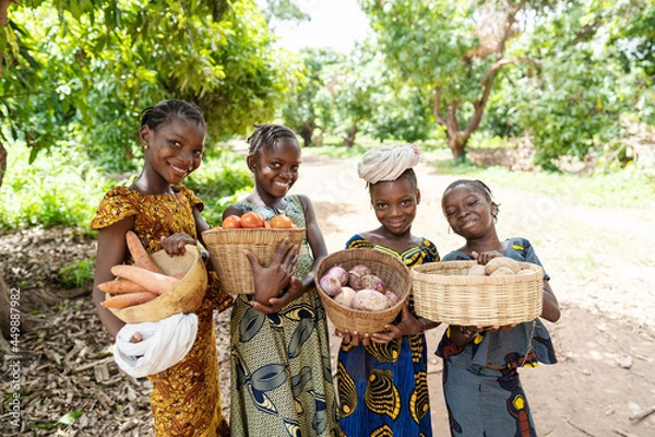 Obraz Group of pretty smiling African girls carrying baskets full of vegetables, on their way to the lokal market