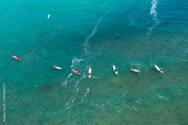 Obraz In the background, surfers sit on their boards waiting for the waves. in the blue sea