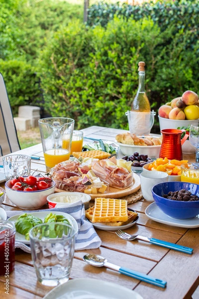 Obraz Food on the table.Laid table with food.Breakfast on the terrace.Avocado croutons.Healthy breakfast.Juice is poured for breakfast.The family is eating delicious food.There are many dishes on the table.