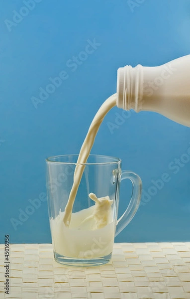 Obraz pouring milk from a bottle into a cup