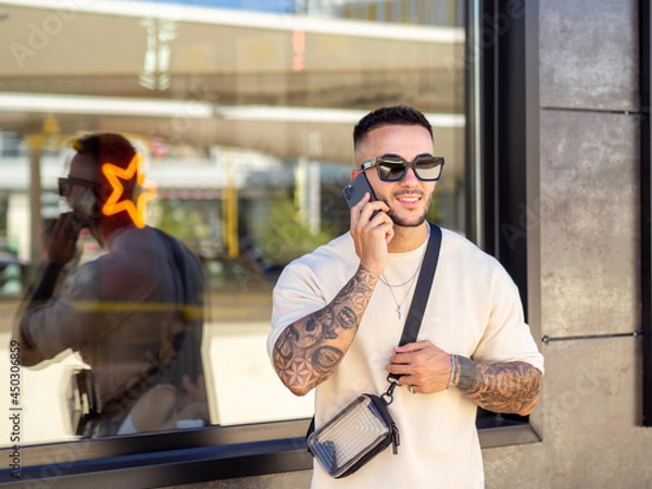 Fototapeta Hombre joven con tatuajes hablando por teléfono 
