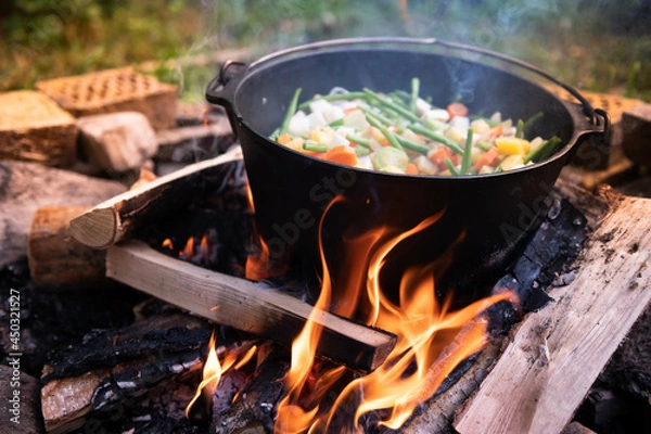 Fototapeta Dutch oven cooking on a campfire with open lid and stew