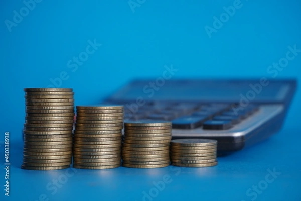 Obraz stacks of money coin with calculator and book bank, Business and financial investment concept on blue background