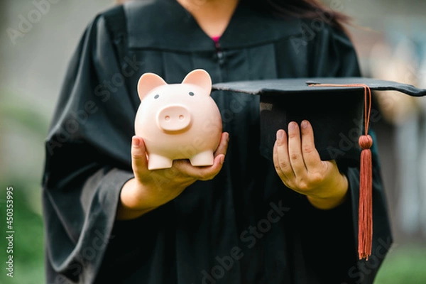 Obraz graduates holding piggy banks saving concept