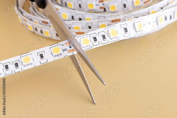 Fototapeta Cutting LED light tape with scissors