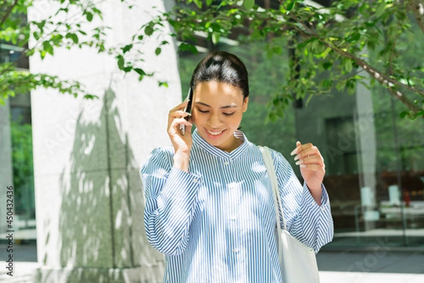 Fototapeta オフィス街で電話をするハーフ女性