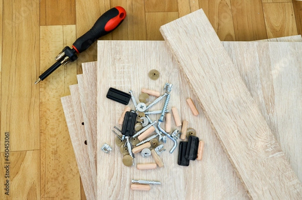 Fototapeta Chipboard sheets, tools and parts for assembly of cabinet furniture. Self-assembly of furniture at home. details of bedside table are spread out on floor. tool for assembling glued wood materials
