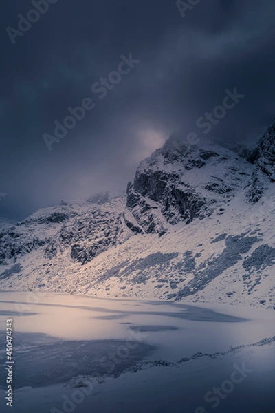 Obraz Dramatic cloudscape over Kościelec Peak, High Tatra Mountains, Poland. Czarny Staw Gąsienicowy in the valley. Selective focus on the rocks, blurred background.