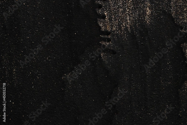 Fototapeta The metal texture of the background painted in black paint with smudges, scratches and splashes of gold sparkles
