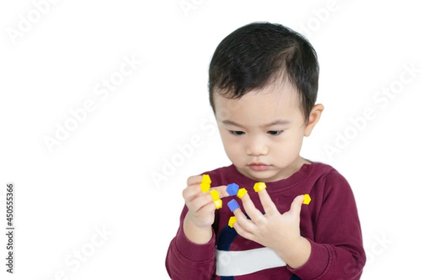Fototapeta Asian children boy learn through play by putting toys on their fingers with white isolated background, child development concept.