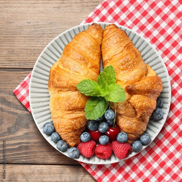 Fototapeta butter croissants on the plate served with berries and mint leaf top view on checkered towel