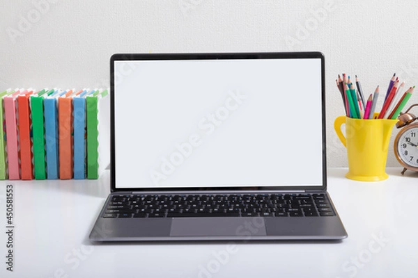 Fototapeta Open laptop mock-up at children's workplace with colored books and pencils. Back to school online learning concept