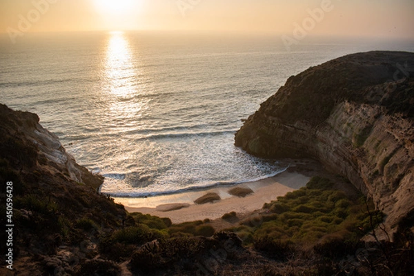 Fototapeta A green cliff in front of the sea, during a beautiful sunset in Quirilluca beach