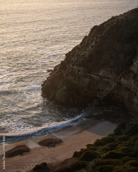 Fototapeta A big cliff in front of the sea and a green coast, during a beautiful sunset in Quirilluca beach