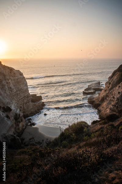 Fototapeta A secret beach protected by cliffs on a beautiful sunset