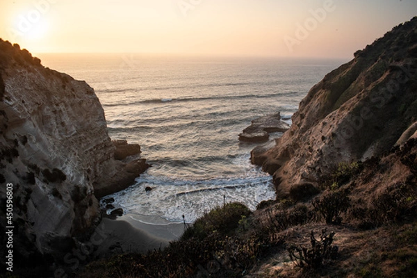 Fototapeta A secret beach between big cliffs on a beautiful sunset