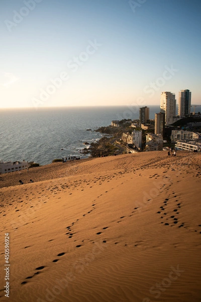 Fototapeta Dunes with the city behind with big buildings and the sea