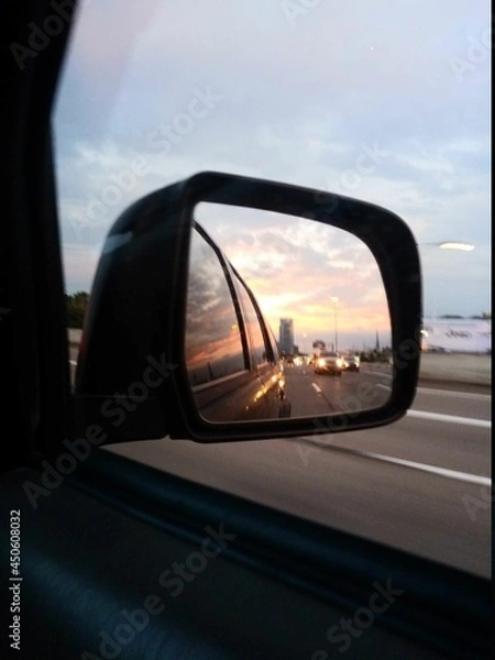 Fototapeta Sunset in the rearview mirror on the highway