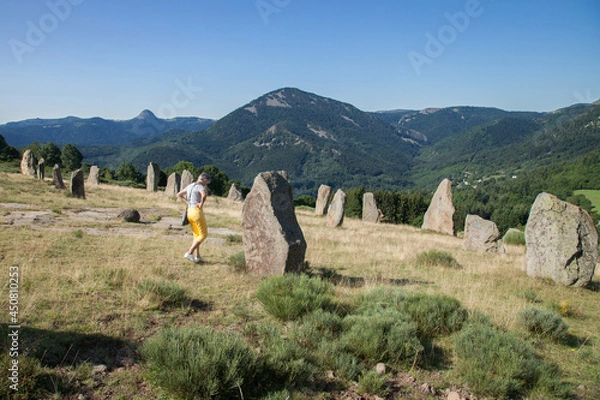 Fototapeta Touriste promenant dans un champ de menhirs dans un paysage des monts d'Ardèche
